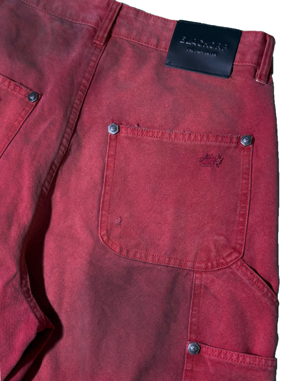 Close-up of red pants with a brand tag on a white background
